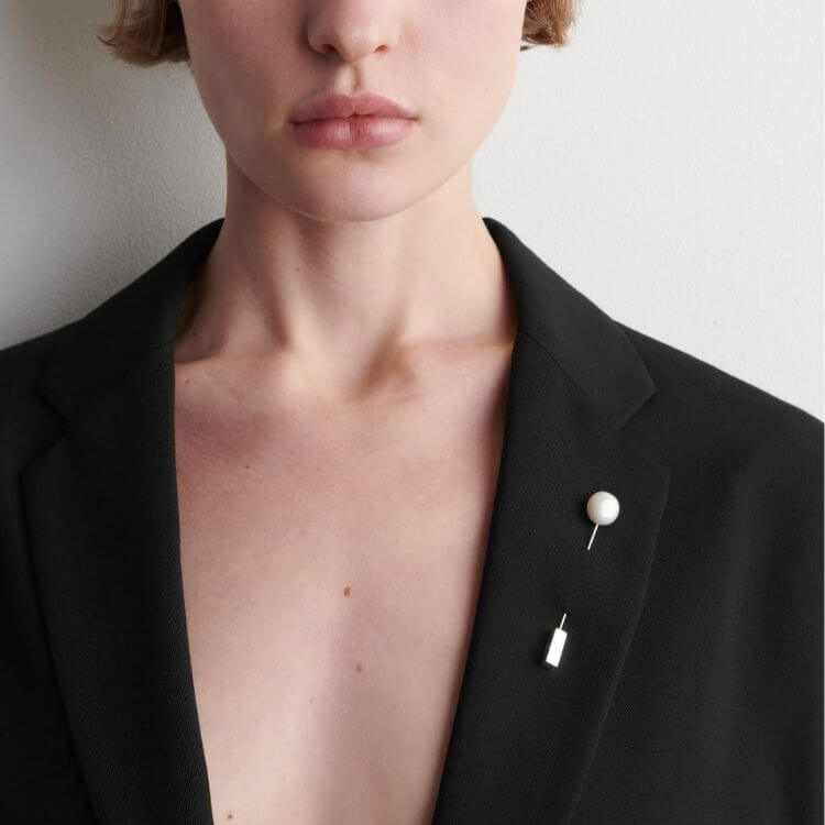 A minimalist brooch featuring a freshwater pearl on a simple metal pin.