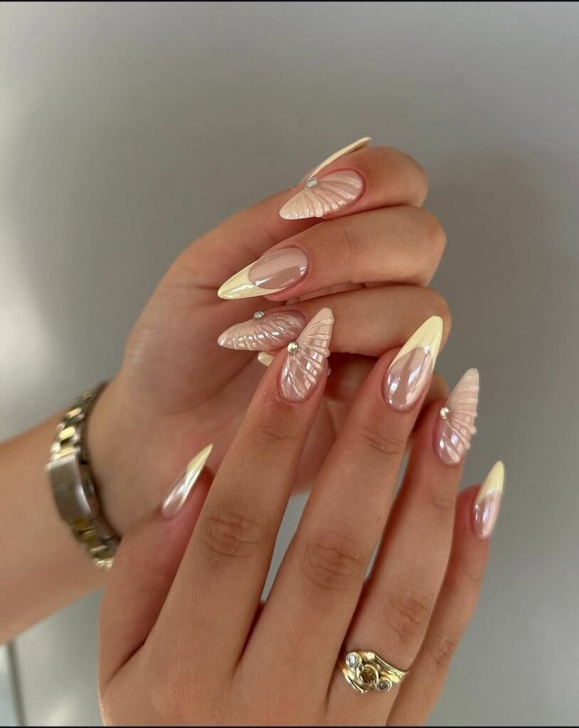 Hands with butter yellow nails wearing gold rings and holding a coffee cup.