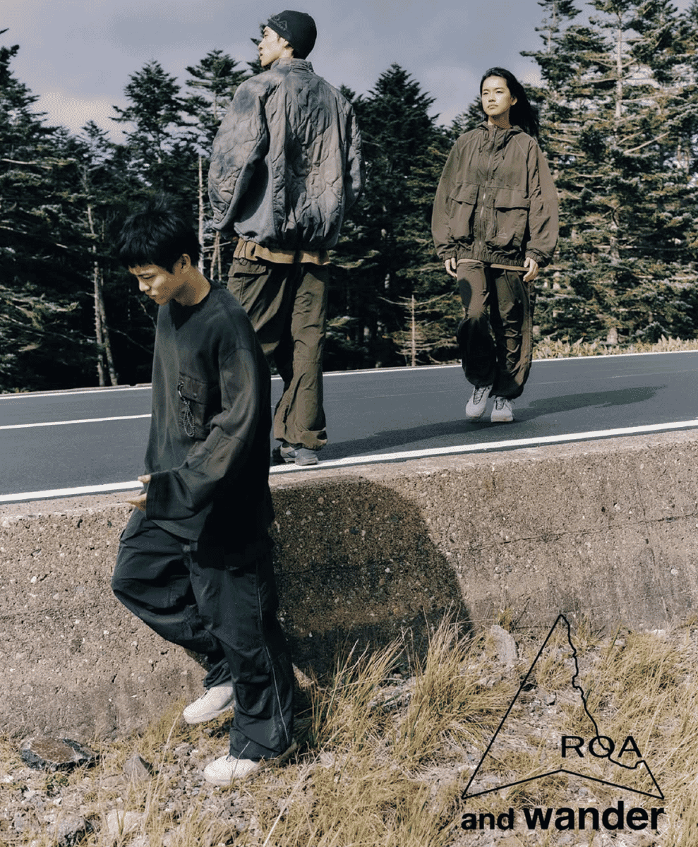 Three models walking on a mountain road in oversized utilitarian quilted jackets and cargo pants.