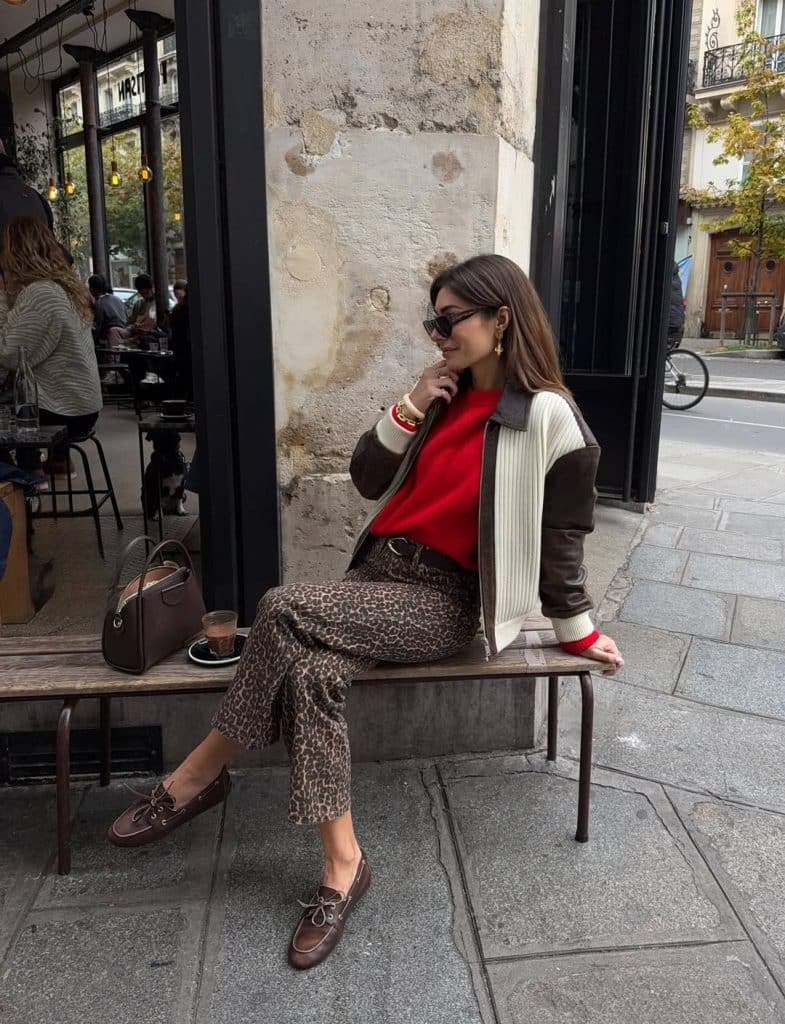 Woman in a red sweater, bomber jacket, and leopard-print trousers.