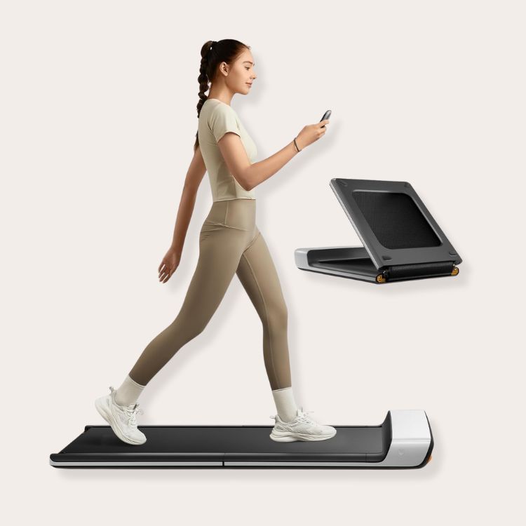 A slim, foldable walking pad tucked neatly under a standing desk.