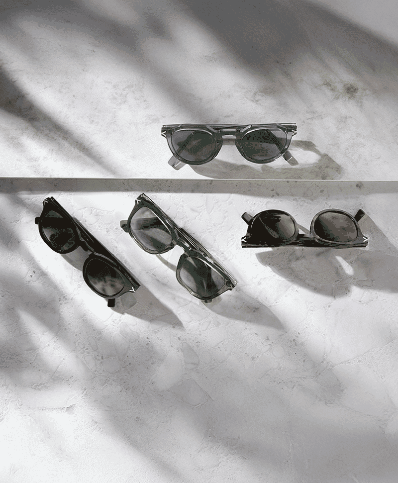 Flat-lay of multiple designer sunglasses on a white surface with artistic shadows.