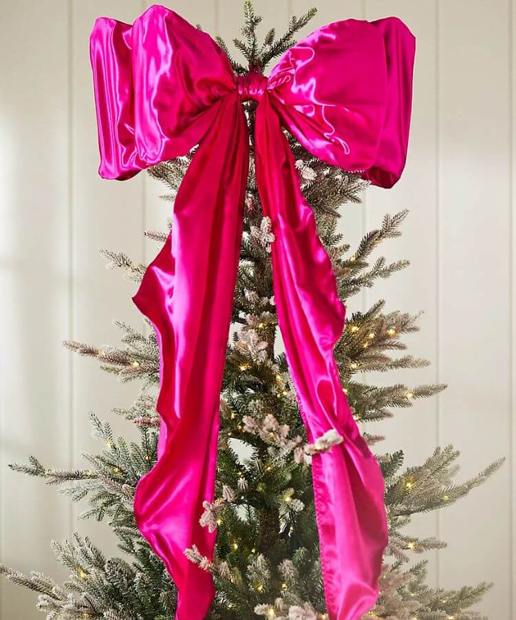 Large red satin bow used as a Christmas tree topper.