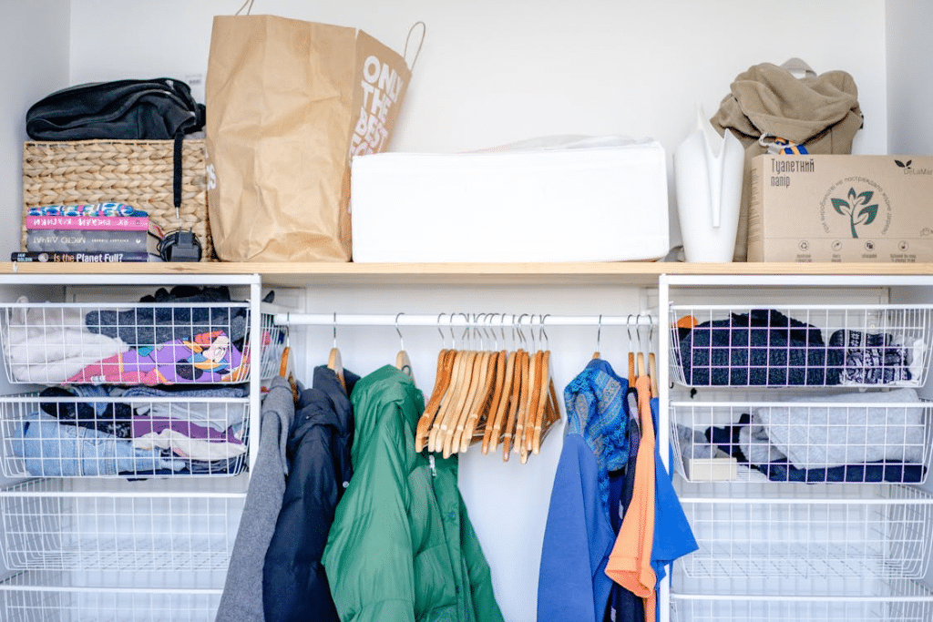 Closet view showing the transition of layers with lighter spring pieces in the foreground and heavy coats on higher racks.