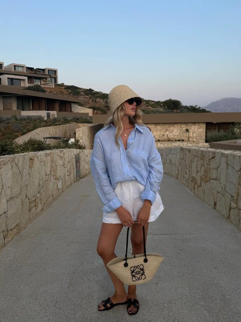 Woman wearing a classic blue linen shirt with white shorts.