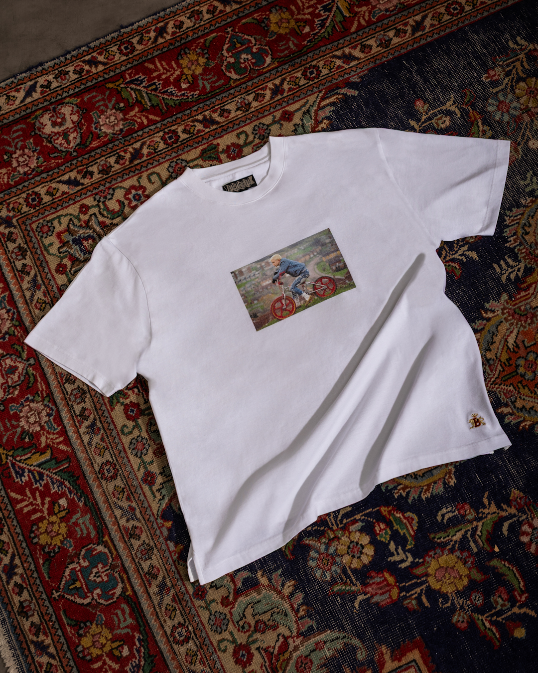 Clean studio shot of a white graphic T-shirt featuring a prominent Gavin Watson photograph on the front.