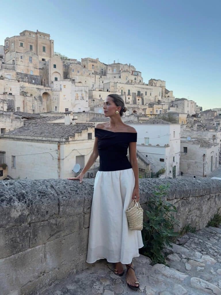 Woman in an off-the-shoulder black top paired with a voluminous white midi skirt.