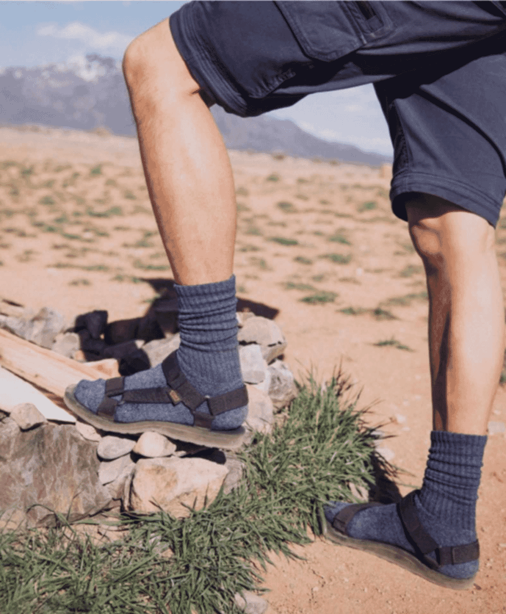 A hiker wearing blue strappy sandals on desert rocks.