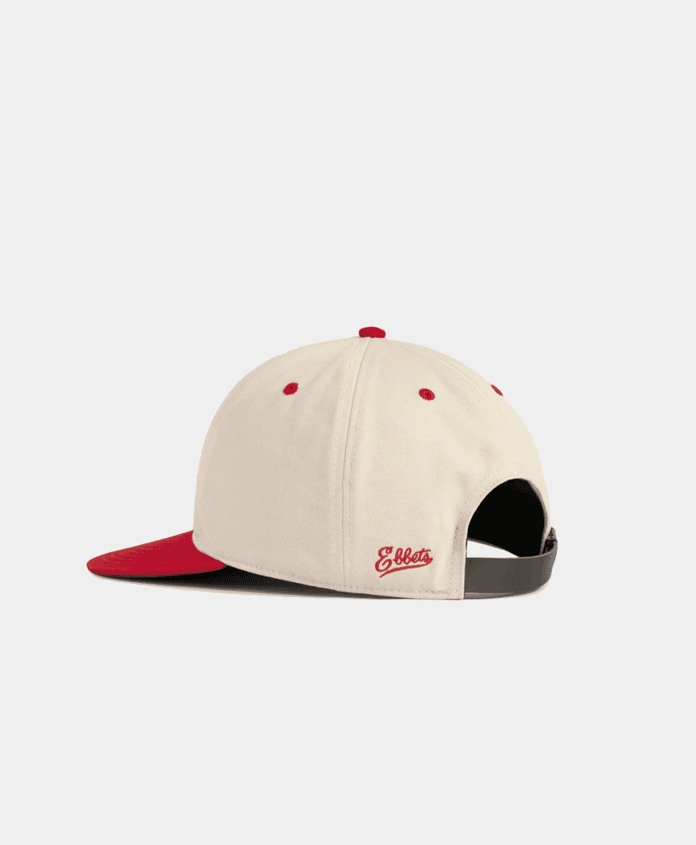 Cream-colored baseball cap with red brim and 'Ebbets' script embroidery on the side.