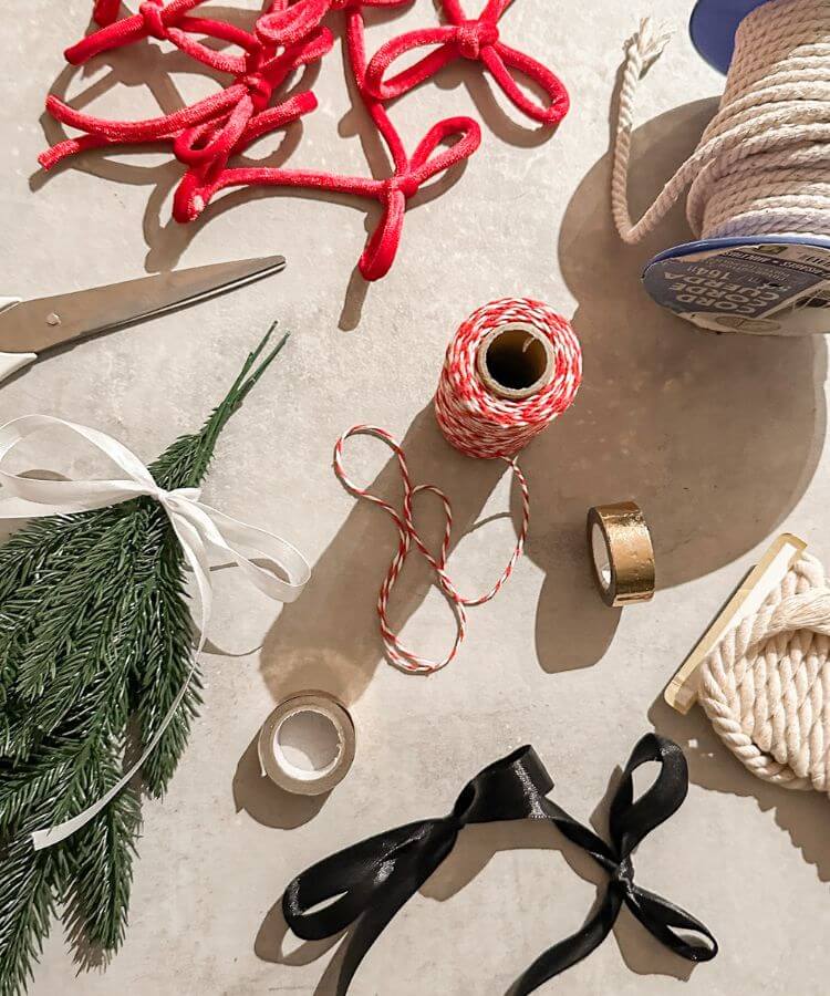 Overhead shot of hands crafting holiday decorations with ribbons and natural materials.