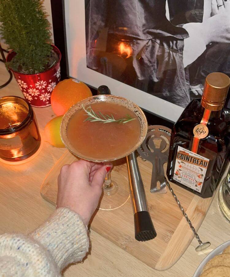 Close-up of a seasonal cocktail being poured into a glass with festive garnishes.