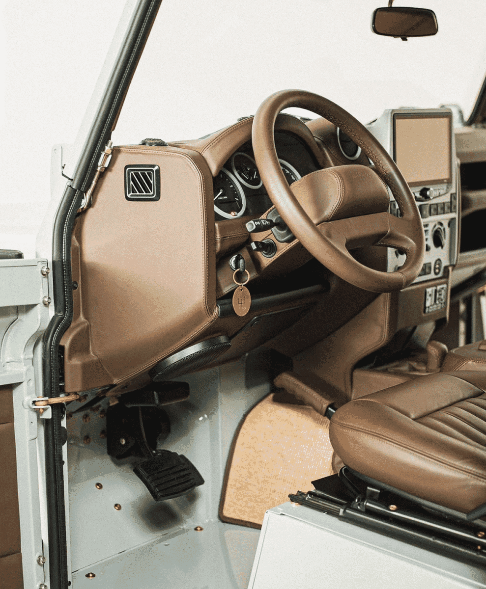 Wide shot of a luxury SUV interior with bespoke tan leather seating and steering wheel.