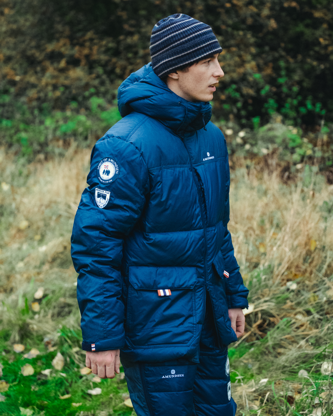 A man in a navy blue Amundsen puffer jacket with heritage patches and a matching beanie.