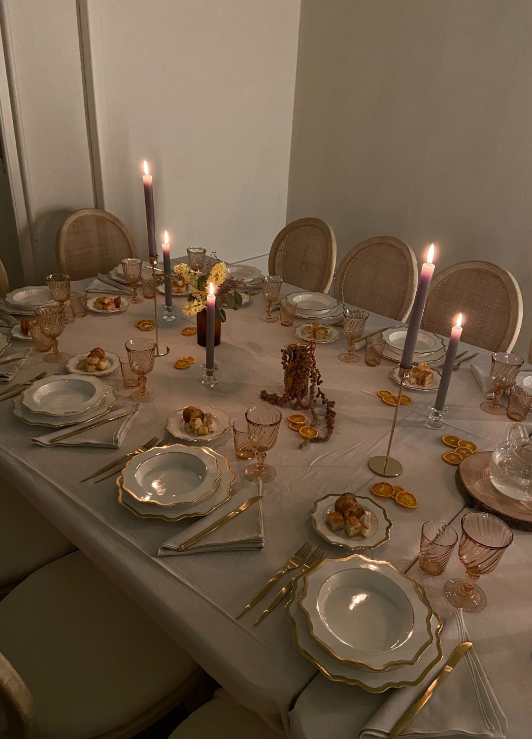 An elegant, dimly lit table setting prepared for a small, intimate dinner party.