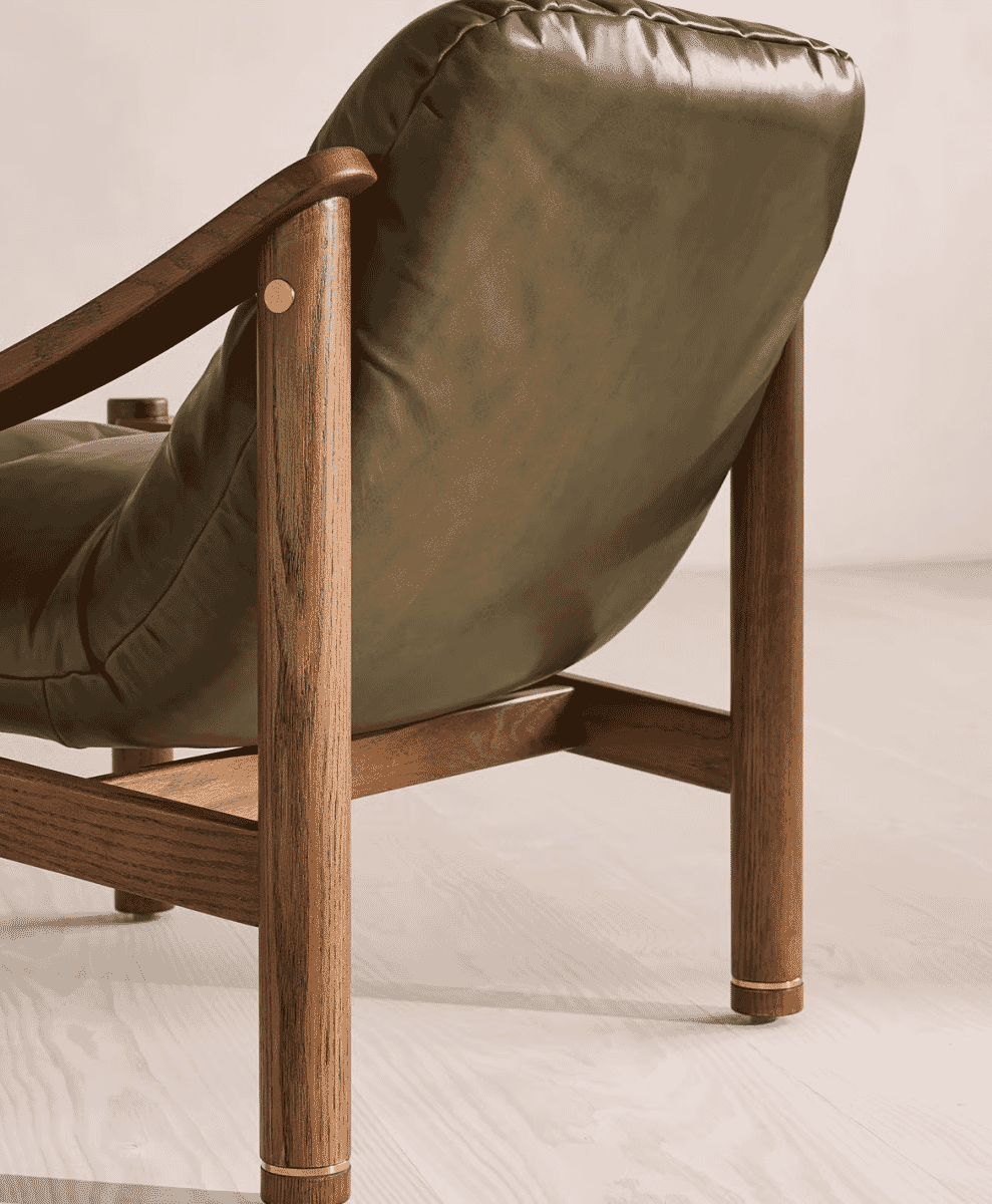 Close-up of a modern armchair with dark-stained wooden legs and olive green leather upholstery.