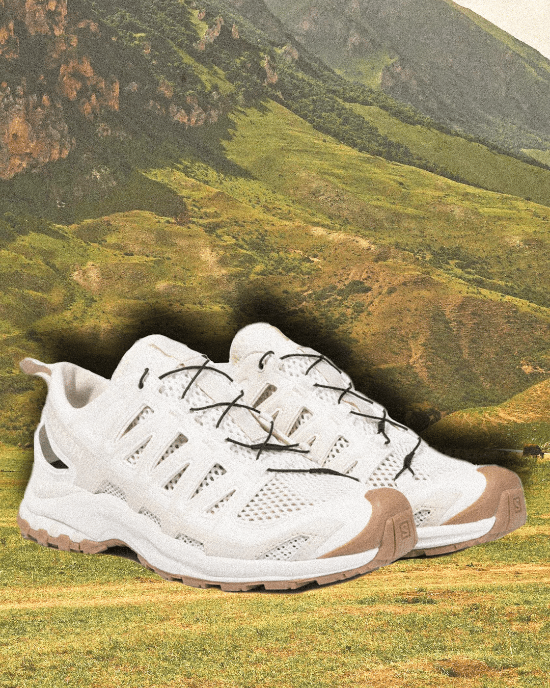 White Salomon X Ultra 5 GTX shoes with tan soles on green hills.