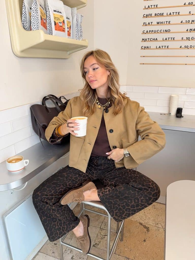 Woman in a full-length camel coat and leopard-print pants.