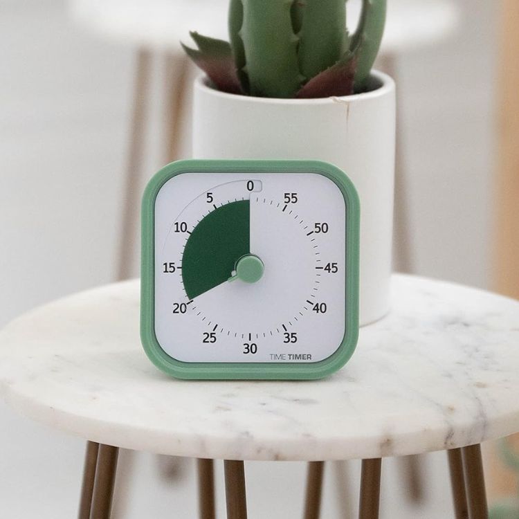 A minimalist white cube timer sitting on a desk next to a keyboard.