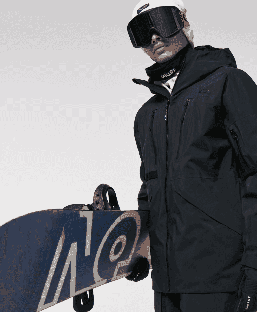A portrait of a model wearing Oakley goggles and a black helmet.