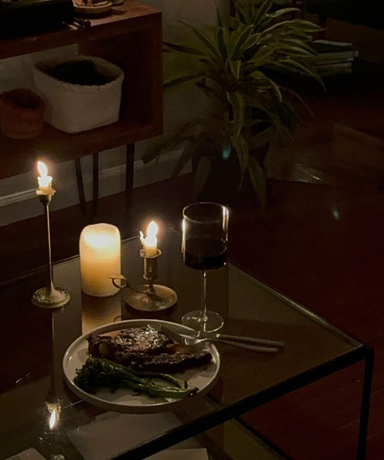A beautifully set table with lit candles and evergreen sprigs for a holiday dinner.