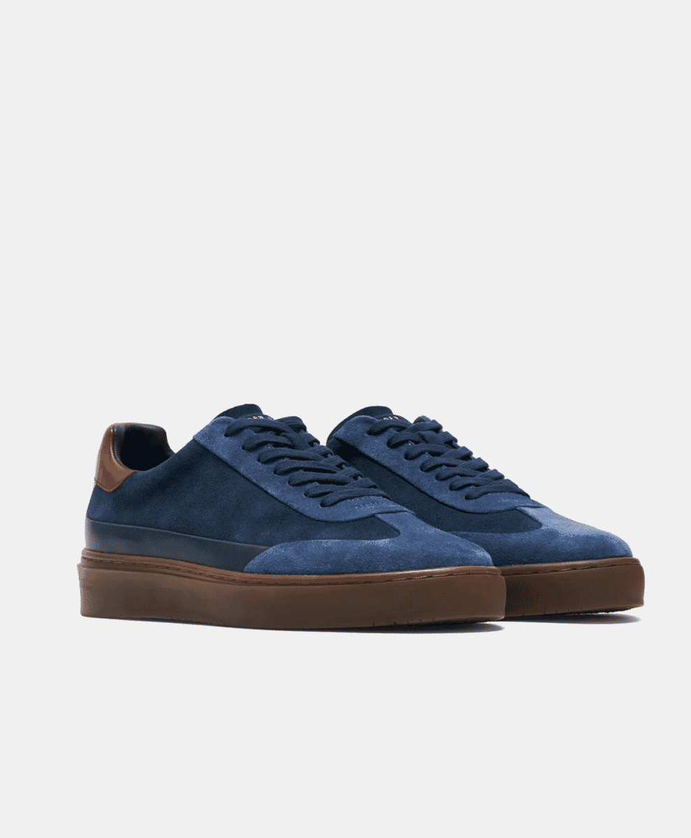 A pair of navy blue suede low-top sneakers with brown rubber soles.