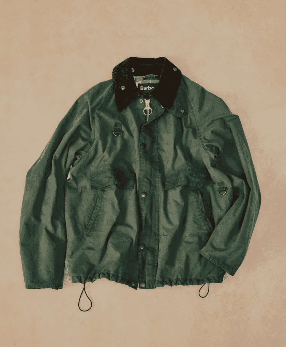 Flat lay of a dark green Barbour jacket showing its silhouette and drawstring hem detail.