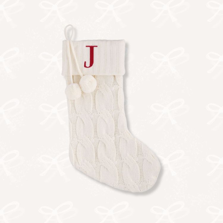 A cream colored cable knit Christmas stocking.
