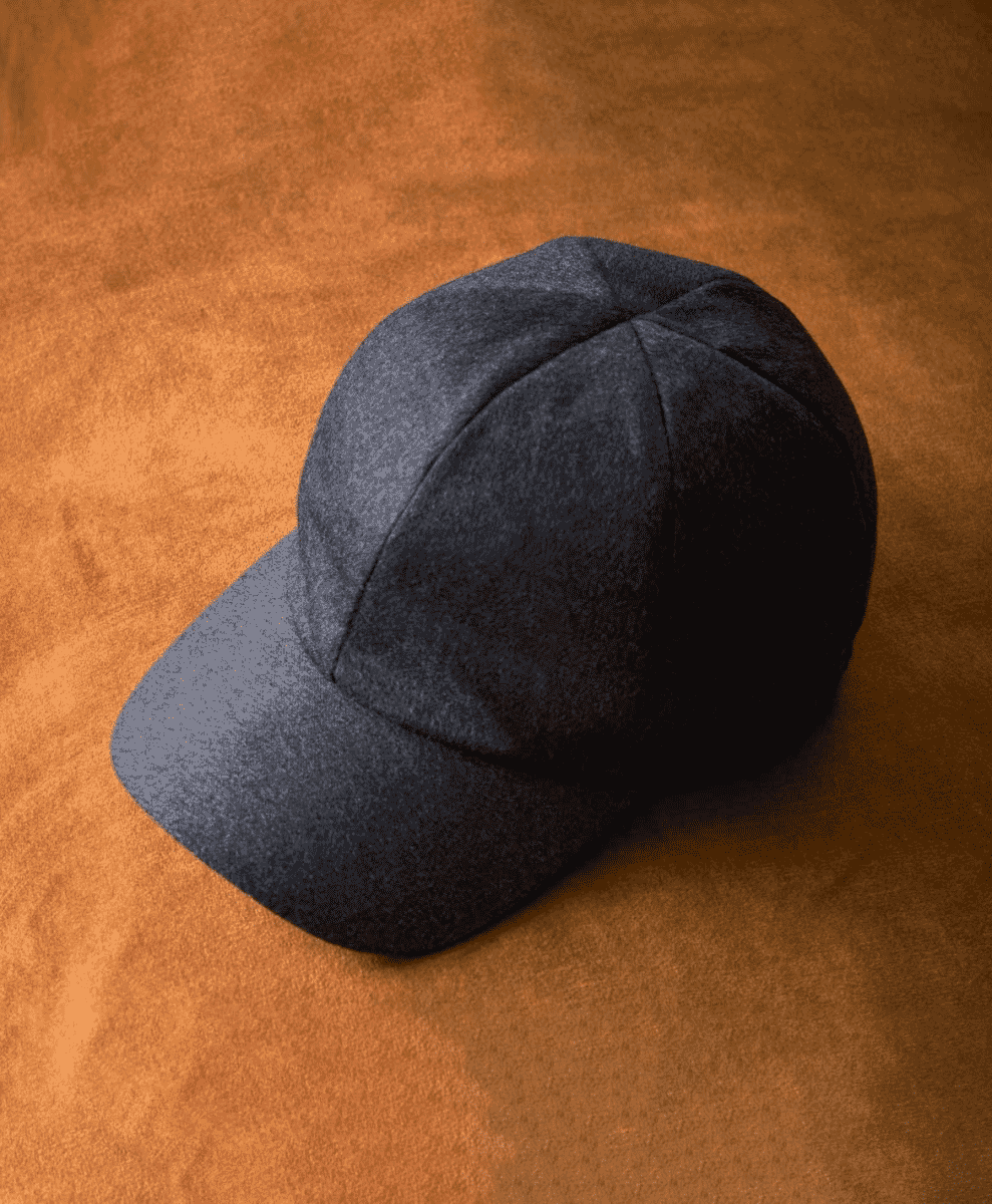 Dark gray wool baseball cap with structured panels on an orange-brown textured surface.