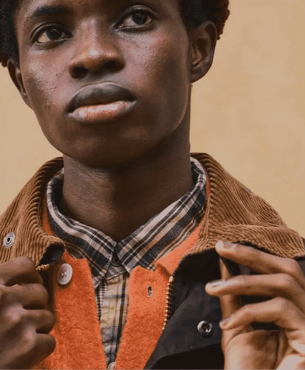 Close-up of a layered outfit featuring a brown jacket, orange fleece vest, and plaid shirt.