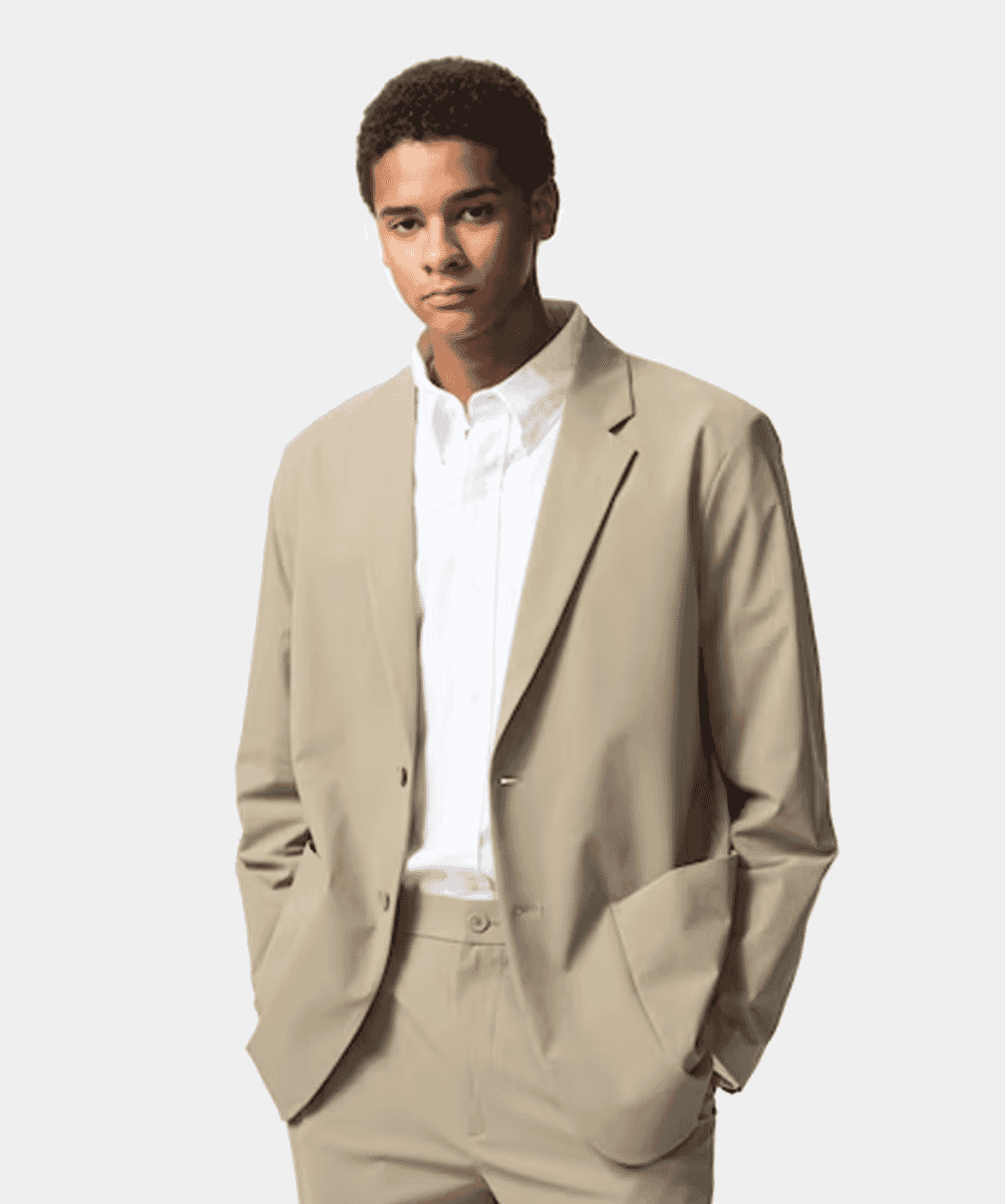 A man modeling a beige blazer and matching trousers with a white shirt.