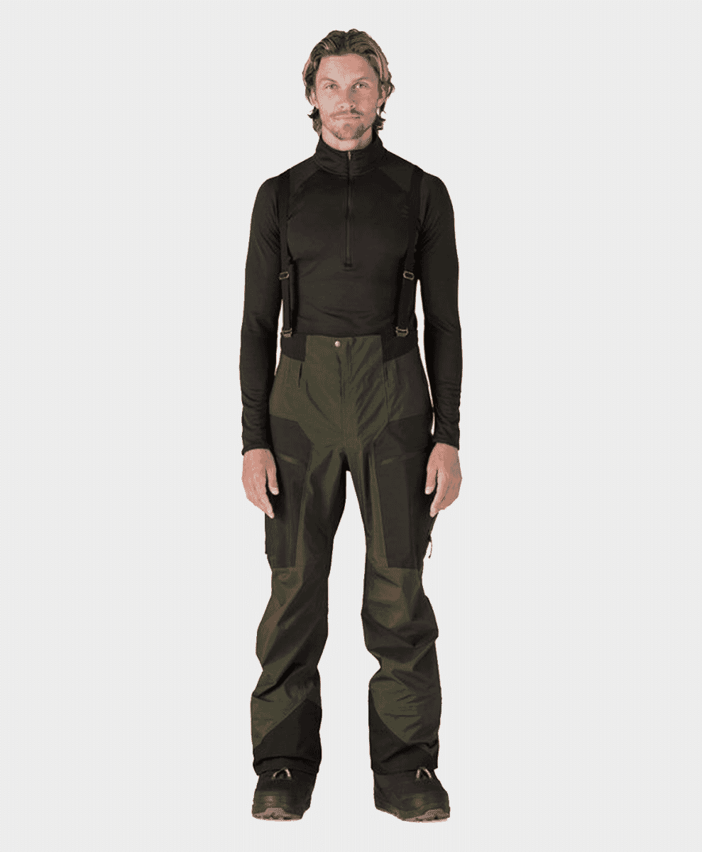 A model wearing a black base layer and olive snowboard pants with suspenders.