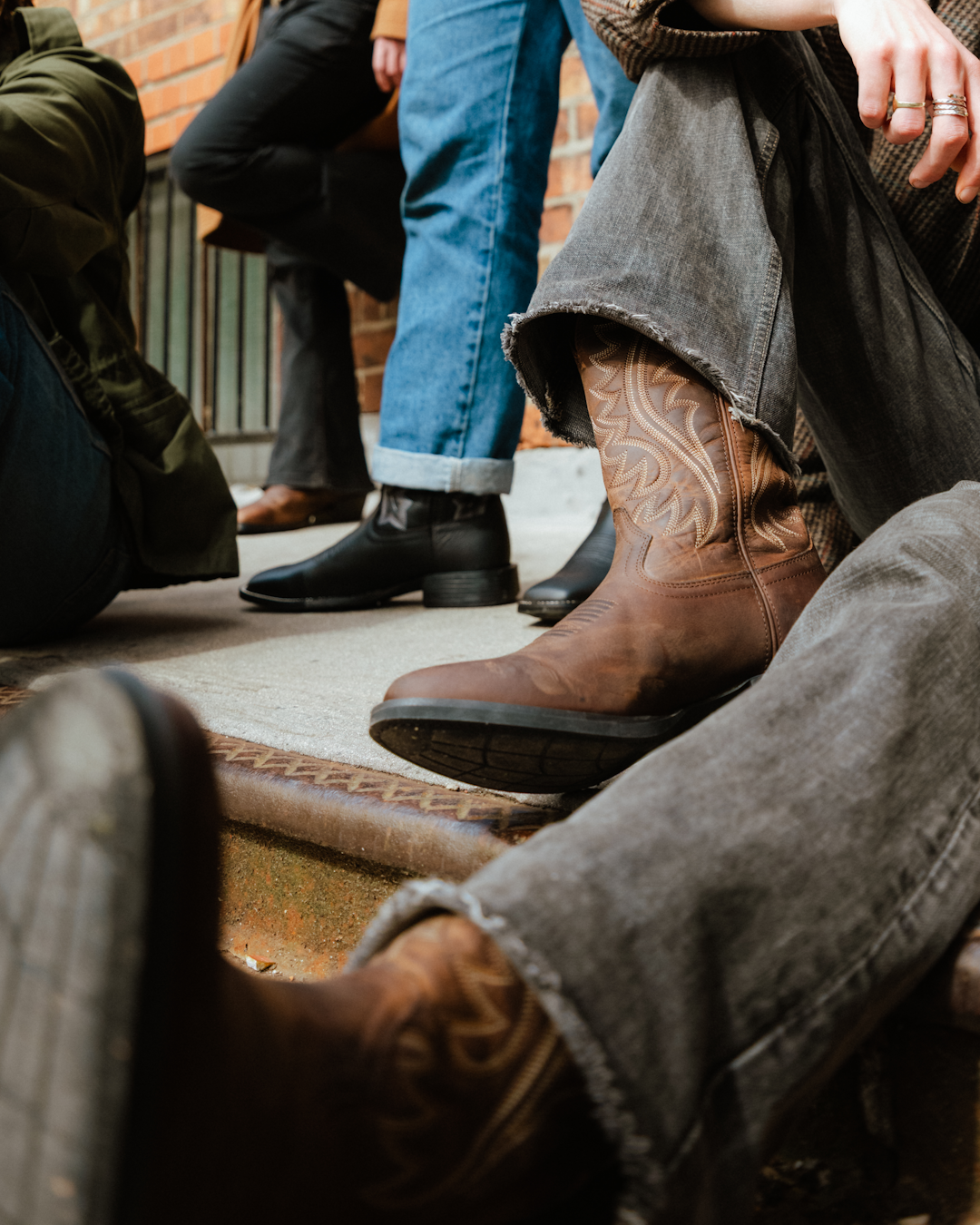Flatlay of cowboy boots, leather belt, and denim shirt.