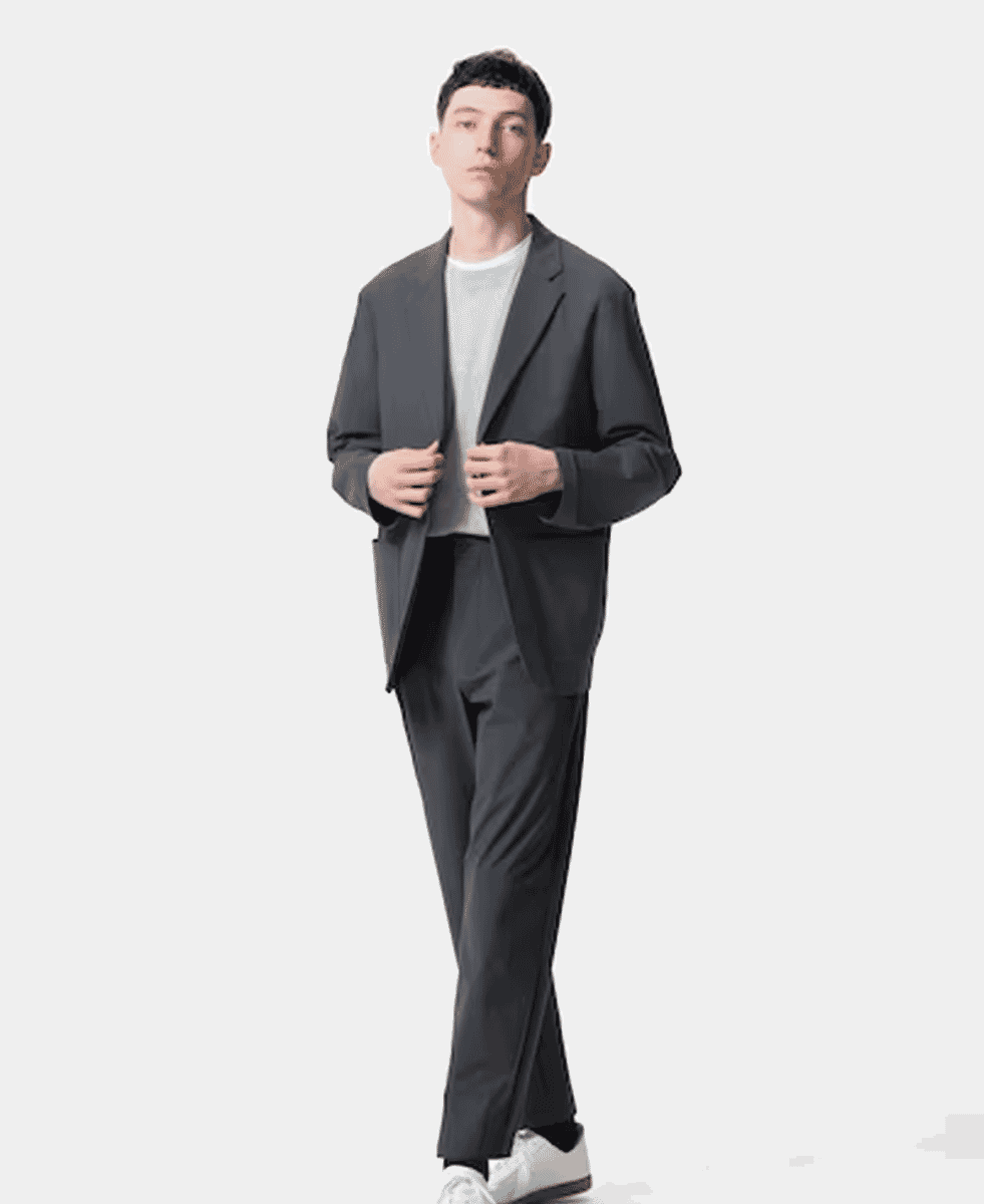 A man in an oversized dark gray suit with a white t-shirt and white sneakers.