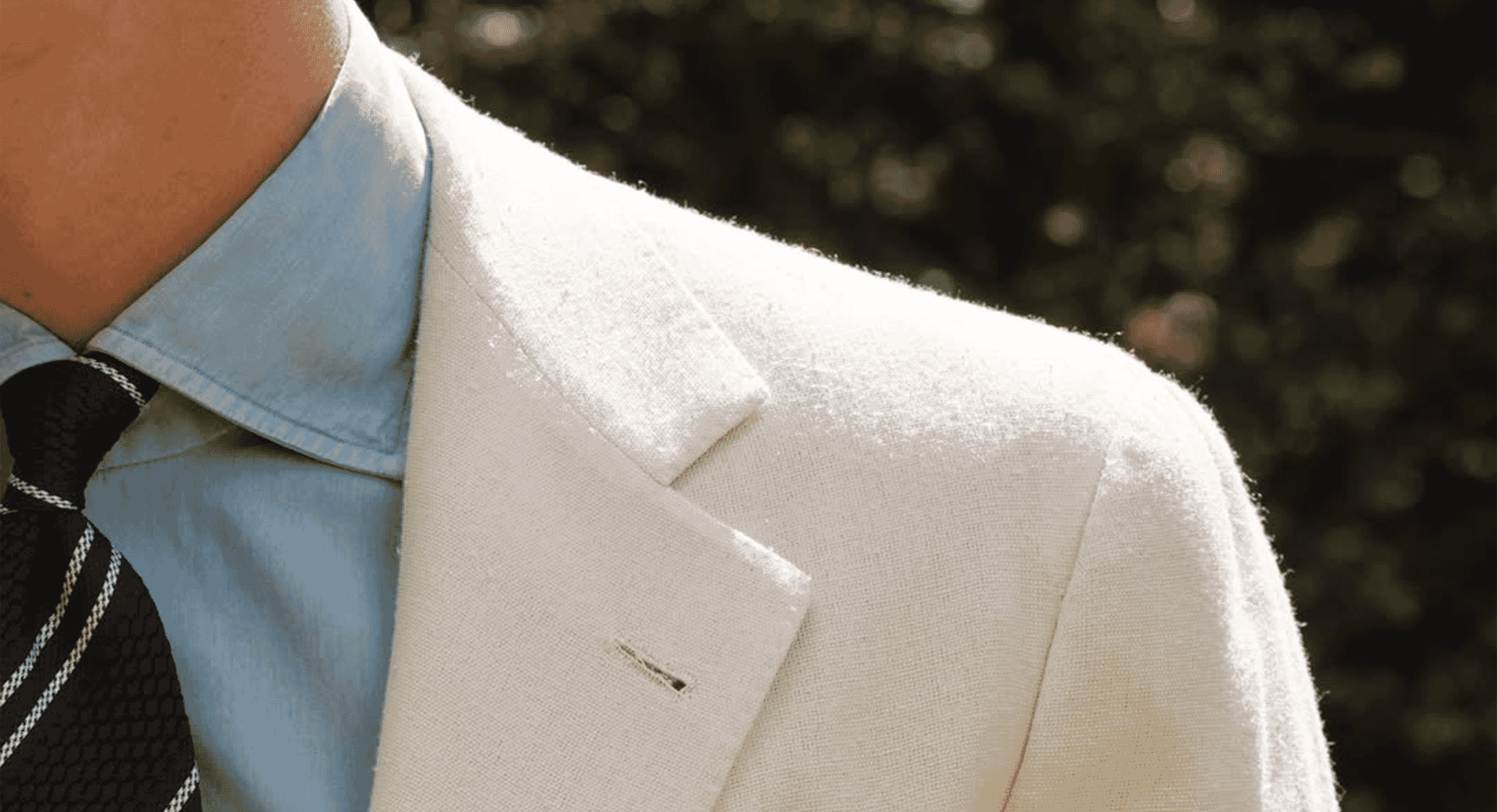 Close-up of a man in a light-colored textured blazer and light blue shirt.