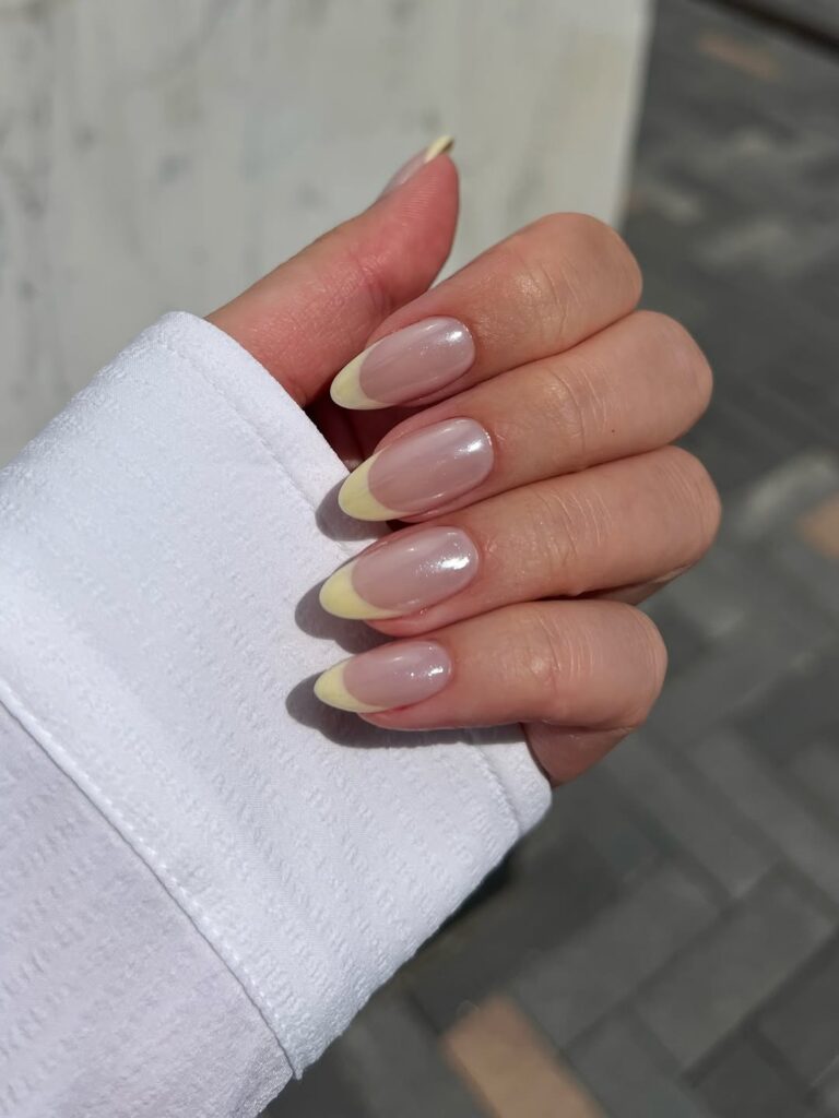 Butter yellow manicure on a model with medium skin tone.