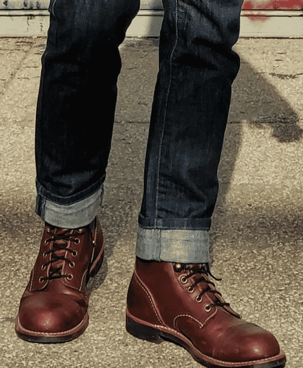 Close-up of cuffed denim jeans and polished brown leather boots.
