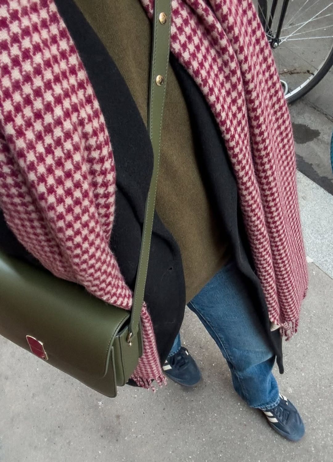 A woman wearing a cozy cable knit sweater and an oversized coat with a classic leather tote bag.