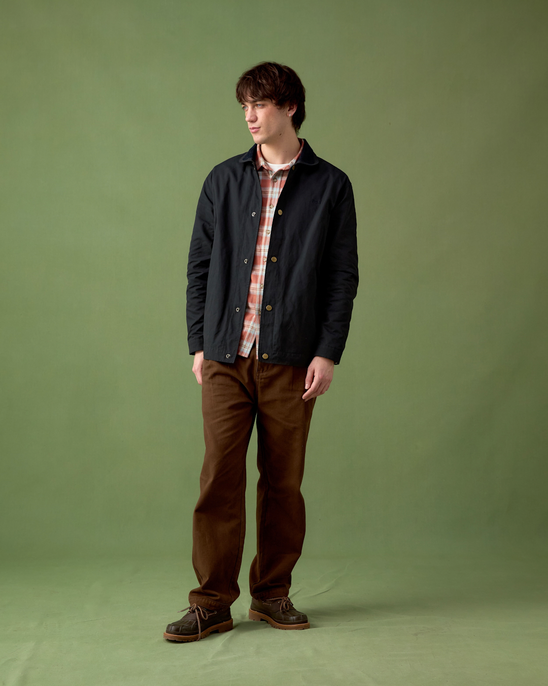 Action shot of a person in a waxed jacket and layered fleece during light rain in the outdoors.