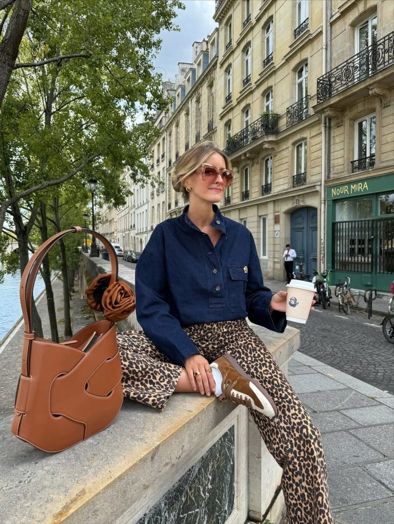 Woman in a navy denim shirt and leopard pants sitting on a canal ledge.