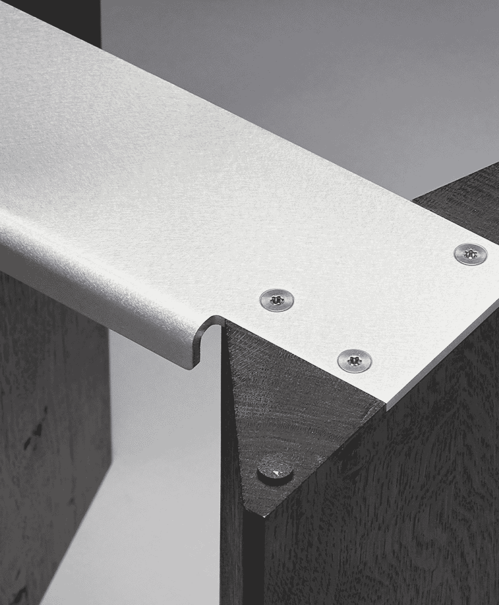 Macro close-up of a metal bracket fastened with screws to dark wood furniture.