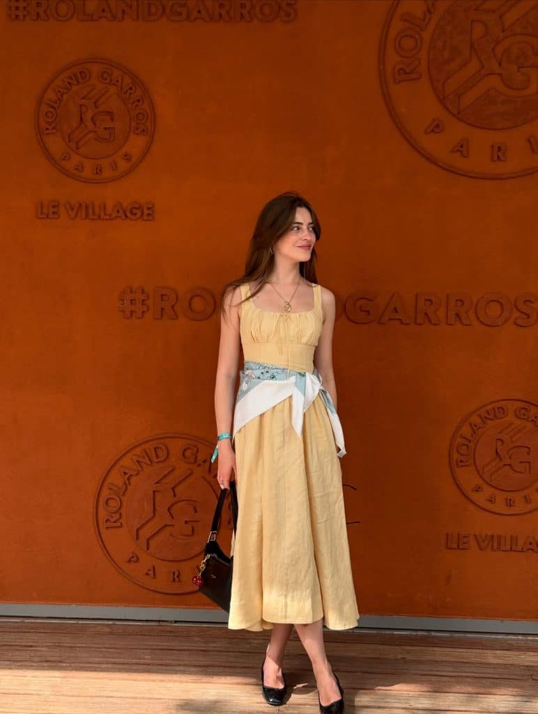 Woman in a soft butter-yellow midi dress styled with a silk scarf as a belt.