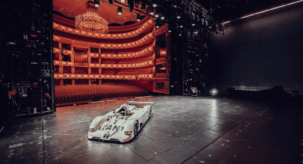 BMW V12 LMR race car displayed on an opera house stage.