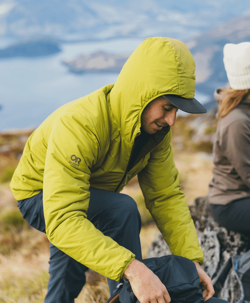 A man in a lime green Outdoor Research jacket on a mountain trail.