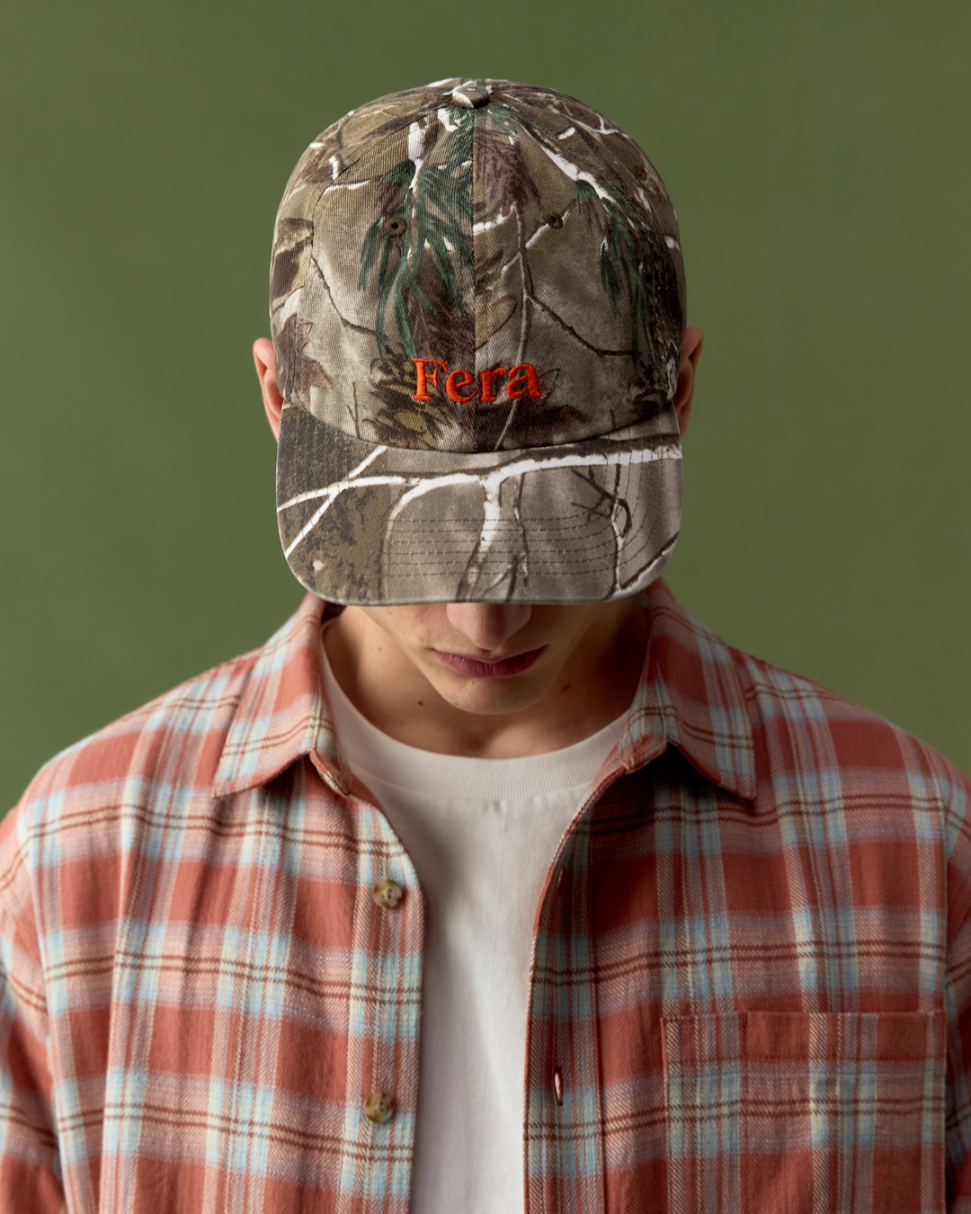 A group shot of various SS26 collection items including jackets, shirts, and caps laid out on a wooden table.