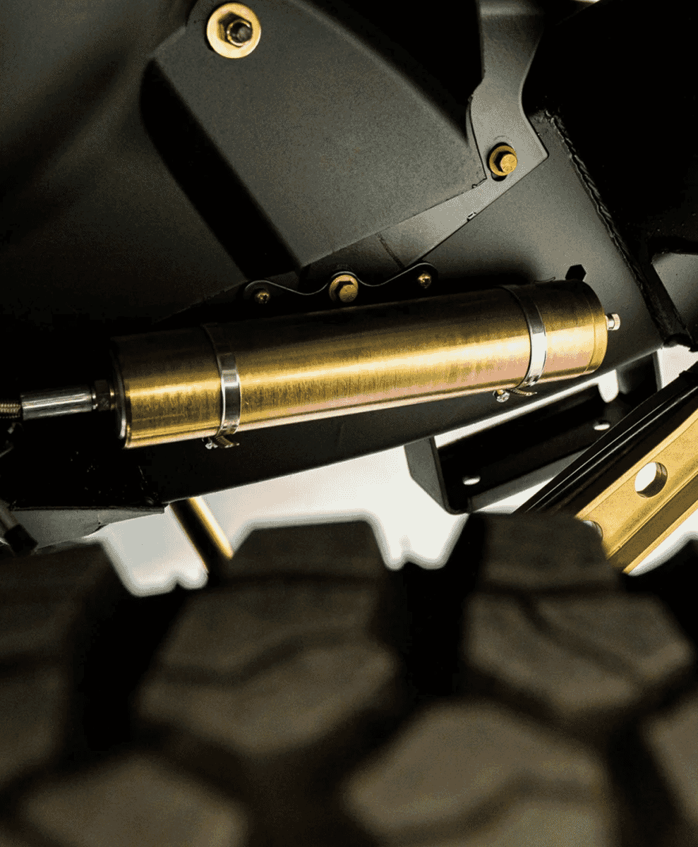 Close-up of a gold shock absorber and suspension components on an off-road vehicle.