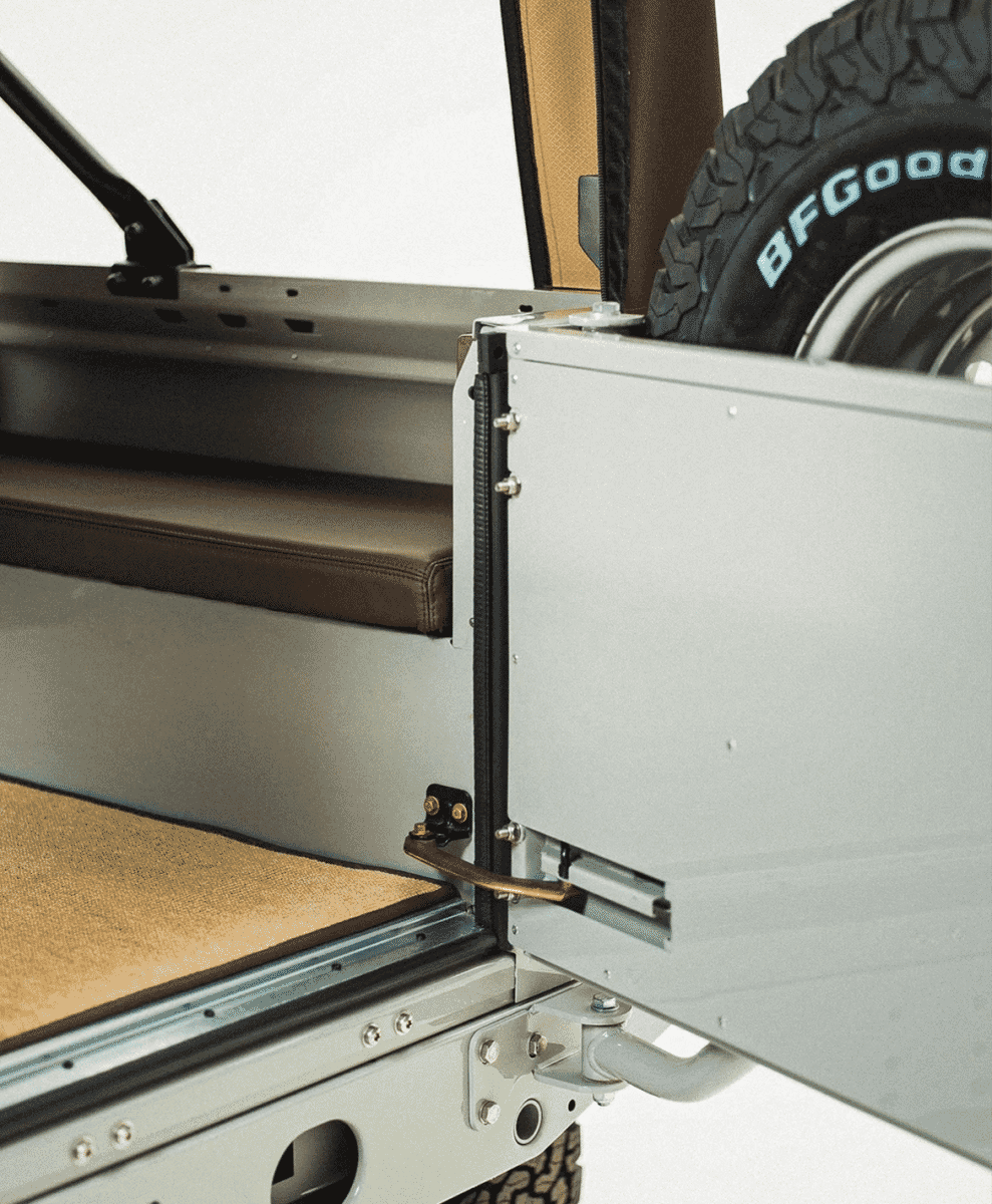 Close-up of the rear of a Defender 90 with a BFGoodrich spare tire and silver metallic body panels.