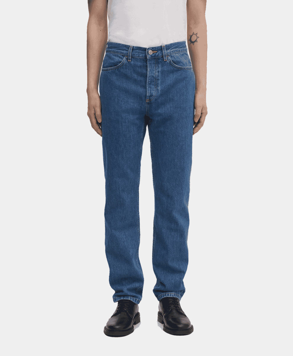 Full-body shot of a man wearing medium-wash blue denim jeans and black shoes.