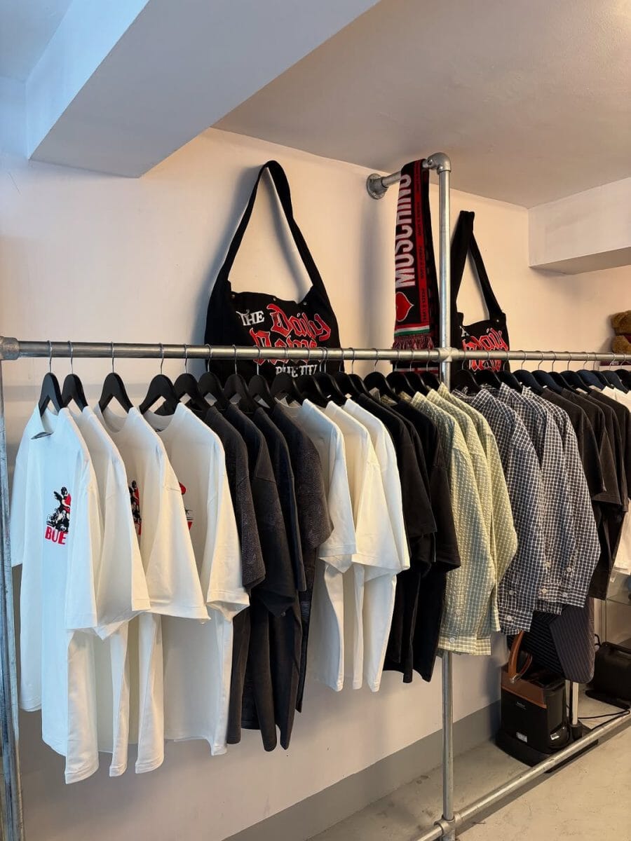 Clothing rack with T-shirts and tote bags in a minimalist retail space.