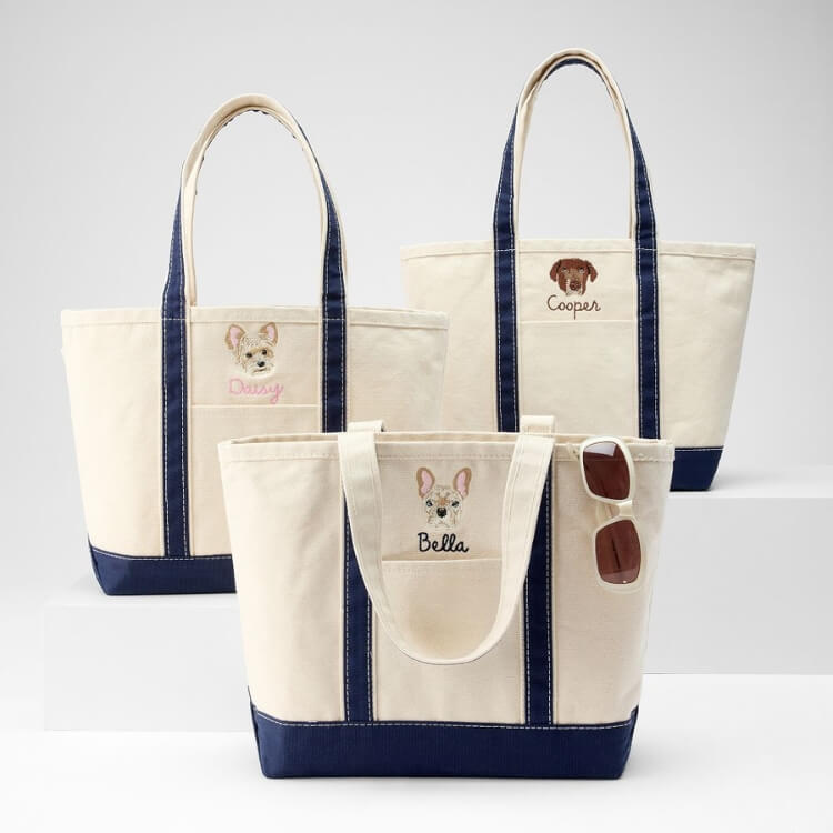 A full shot of a large embroidered canvas tote bag suitable for carrying dog gear.