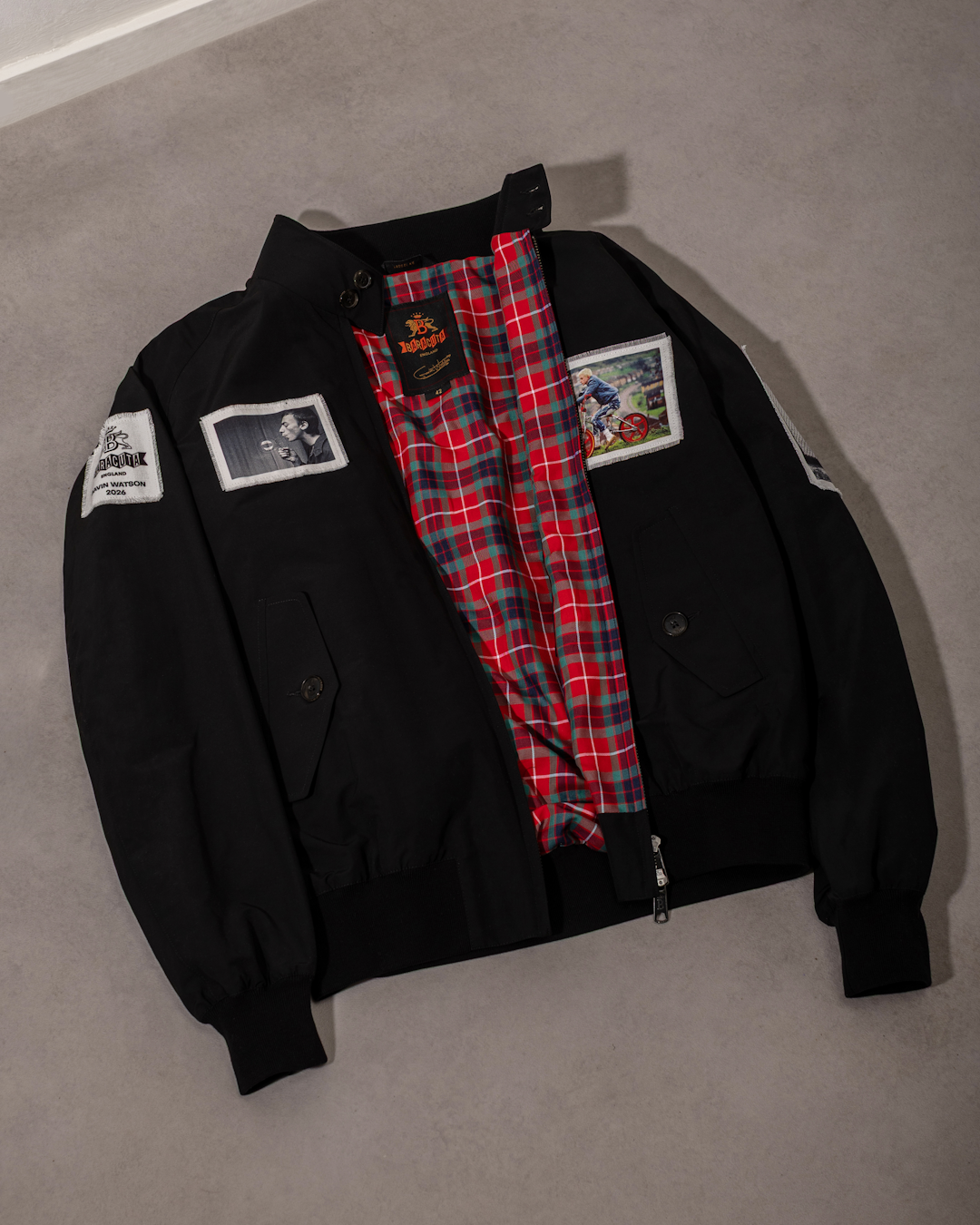 Detailed close-up of the G9 Harrington jacket showing black and white photographic patches stitched onto the sleeve and chest.